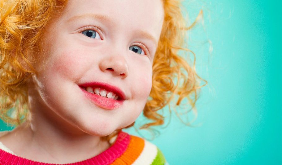 Red-haired girl laughing against a teal backdrop
