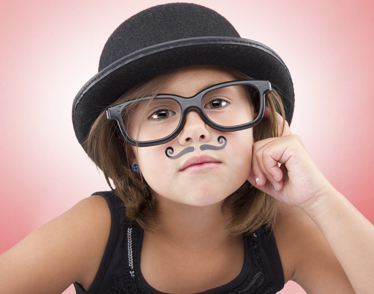 Girl in a bowler hat and glasses making a funny mustache face