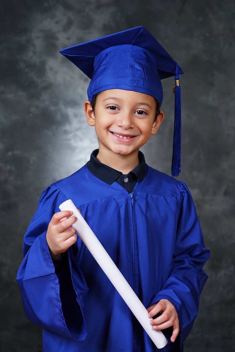 Boy in a blue cap and gown holding his diploma